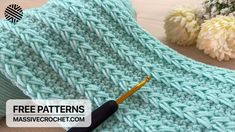 a knitted blanket with a crochet hook next to it