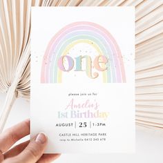 someone holding up a birthday card with the word one in front of it and a rainbow