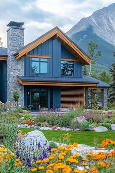 a blue house surrounded by flowers and trees with mountains in the backgrouund