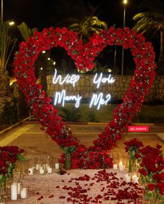 a heart - shaped display with candles and flowers in front of the words i love you marry me?