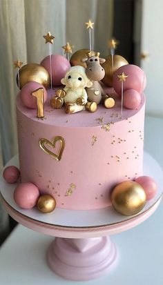 there is a pink cake with gold decorations on it and a teddy bear in the middle