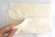 a person is kneading dough on top of a white countertop with one hand