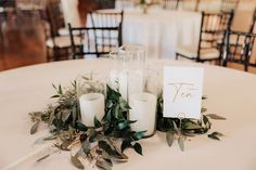 candles and greenery are arranged on the table for an elegant wedding centerpieces