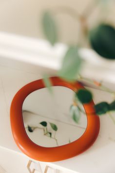 an orange ring sitting on top of a white table next to a green leafy plant