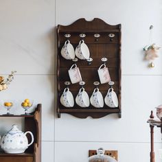 a wall mounted shelf with tea cups and saucers hanging from it's sides