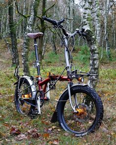 a bicycle is parked in the woods near some trees with leaves on it and one wheel has been turned upside down