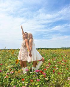 two women are standing in a field with sunflowers