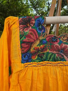 This gorgeous ultra bright, canary yellow top is made with light fabric (pink), and along with the loose fit, it makes it very breathable. The full embroidery around the collar features colorful birds and flowers. This blouse was 100% handcrafted in Mexico by artisans and ethically acquired. Two small green and blue tassels decorate each 3/4 length sleeve. Measurement pictures included. Yellow Long Sleeve Tops With Floral Embroidery, Embroidered Yellow Summer Blouse, Summer Embroidered Orange Blouse, Yellow Bohemian Tops With Floral Embroidery, Orange Embroidered Summer Blouse, Bohemian Yellow Tops With Floral Embroidery, Spring Embroidered Orange Blouse, Yellow Embroidered Summer Blouse, Embroidered Yellow Blouse For Summer