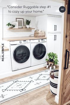 a washer and dryer in a room with white walls, wood floors and cabinets