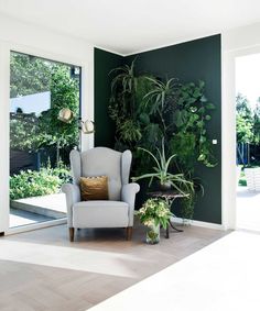 a living room with green walls and plants on the wall, along with a chair