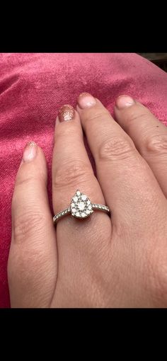 a woman's hand with a diamond ring on top of her finger and pink blanket in the background