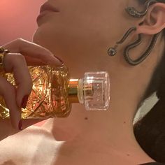 a close up of a person holding a bottle in her hand and wearing earrings