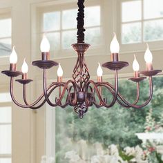 a chandelier hanging from a ceiling in a room with windows and flowers on the table