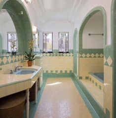 this bathroom has green and yellow tile on the walls, along with an oval mirror