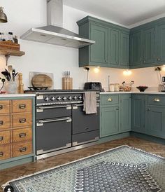 a kitchen with green cabinets and an area rug on the floor in front of the stove