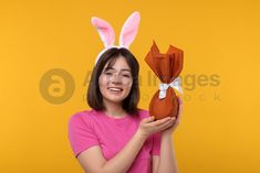 a woman in pink shirt holding up an origami rabbit