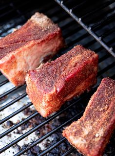 three pieces of meat cooking on a grill