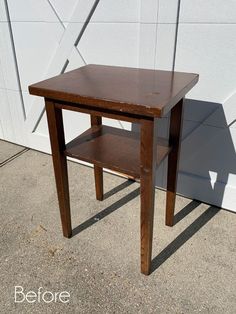 a small wooden table sitting in front of a white wall