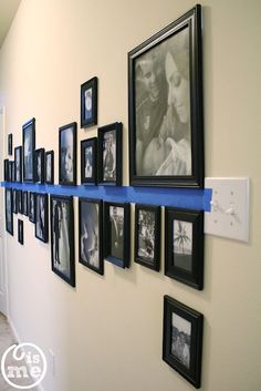 there are many pictures on the wall with blue tape around them and some black and white frames