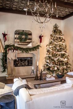 a living room decorated for christmas with a tree and stockings on the fireplace mantel