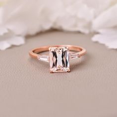 a pink and white diamond ring sitting on top of a table next to some flowers