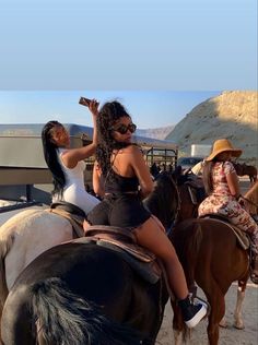 two women are riding horses and one is drinking