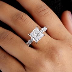 a woman's hand with a diamond ring on top of her finger and an engagement band