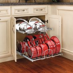 an open cabinet with many red pots and pans in the bottom rack on it