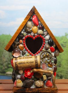 a birdhouse made out of rocks and wine corks with a heart on it