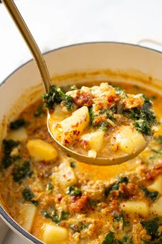 a ladle full of soup with potatoes and spinach