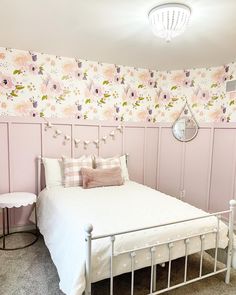 a white bed sitting in a bedroom next to a wall with flowers painted on it