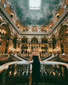 a woman in a black dress is standing at the top of stairs