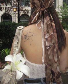 the back of a woman's neck with a white flower in her left hand