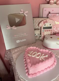 a heart shaped cake sitting on top of a table next to a box with the number 100