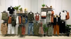 clothes are hanging on the wall next to plants