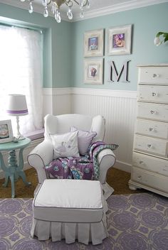 a chair and ottoman in a room with pictures on the wall