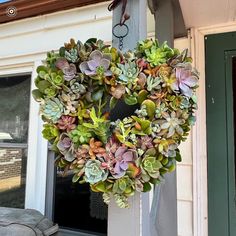 a wreath with succulents hanging from the side of a house