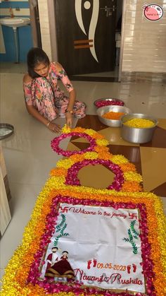 a woman sitting on the floor in front of a decorated cake with flowers around it