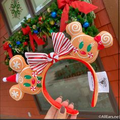 a hand holding up a mickey mouse ears headband with candy canes on it