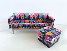 an upholstered couch and footstool are sitting on a white surface,