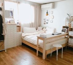 a bedroom with a bed, desk and dresser in it's center area next to a window