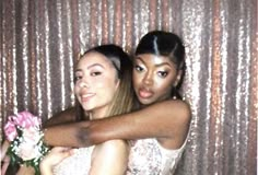 two beautiful women standing next to each other in front of a wall covered with sequins