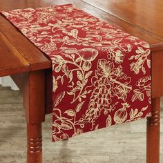 a wooden table with a red and gold floral design on it, sitting next to a wood dining room table