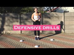 a woman standing in front of a fence holding a pink sign that says defensive drills