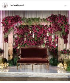 a couch sitting in front of a bunch of flowers on a stage with candles around it