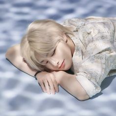 a young woman laying on top of a body of water next to a swimming pool