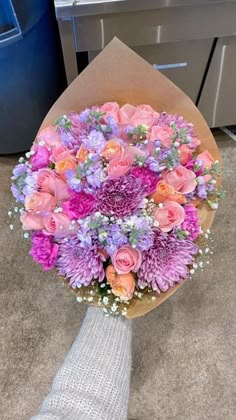 a bouquet of pink and purple flowers in someone's hand