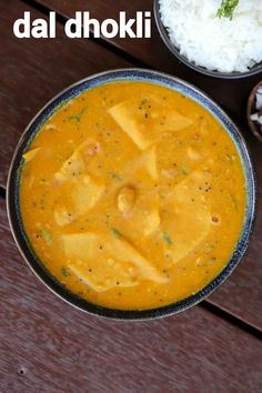 there is a bowl of curry and rice on the table next to some spoons