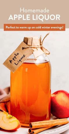 homemade apple liquor in a glass jar with cinnamon sticks and an apple on the side