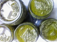 four jars filled with green liquid sitting next to each other